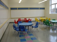 Small, multicolored tables and chairs with whiteboards on walls
